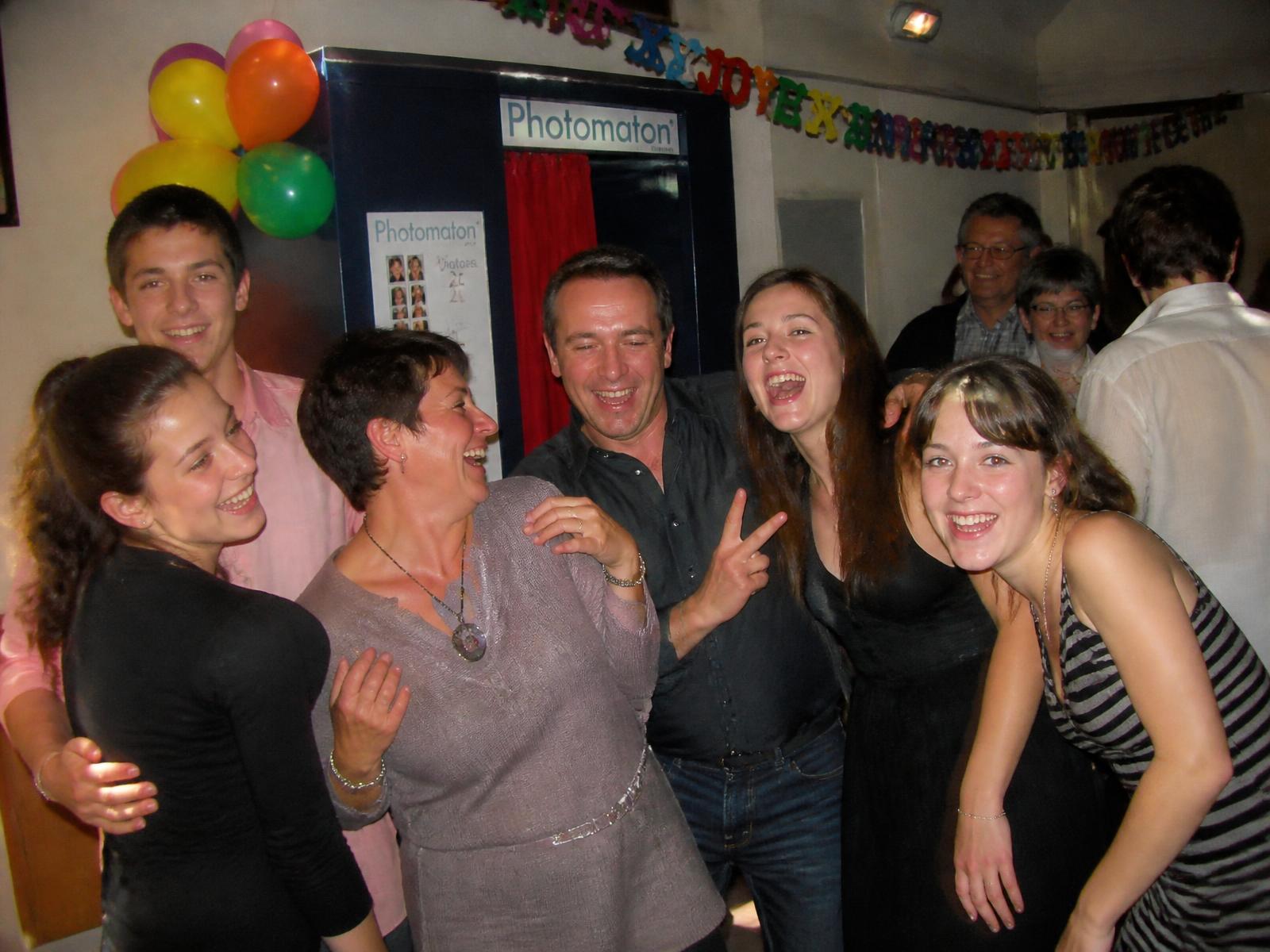 Groupe d'amis riant devant un photobooth lors d'un anniversaire